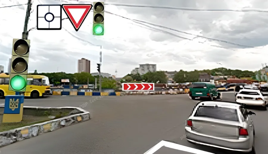 Водій сірого автомобіля здійснює в’їзд на перехрестя з круговим рухом. Чи потрібно в такому випадку вмикати лівий покажчик повороту?